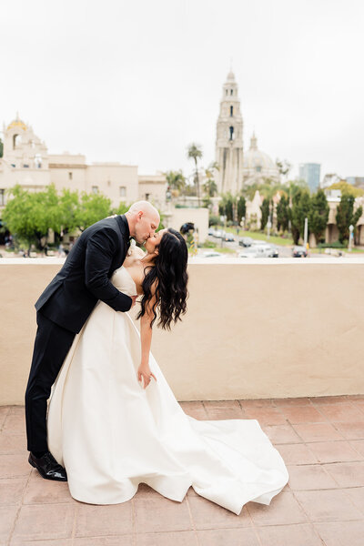 Bride and groom doing a dip kiss on their wedding day at The Prado wedding venue at Balboa Park
