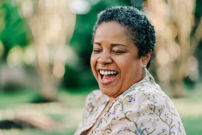 Female black woman joyfully laughing wearing floral blouse