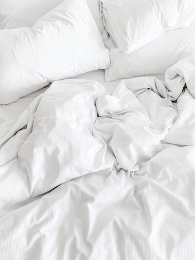 white pillows and sheets left unmade on a bed