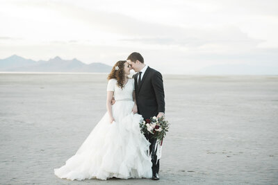 Bride and groom pose at the Bonneville Salt Flats on their wedding day.