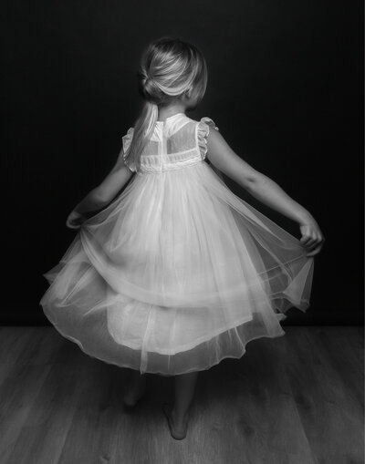 child swirling in a white free dress in a studio