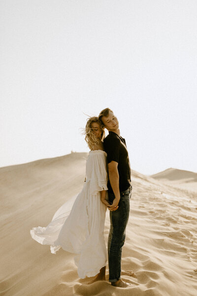 Couple  standing back-to-back with each other on a windy day at the sand dunes