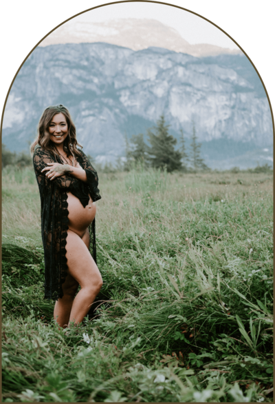 Shae Savage in a field by the mountains while pregnant