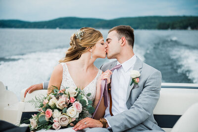 bride and groom just married kissing on a boat at lake bomoseen lodge