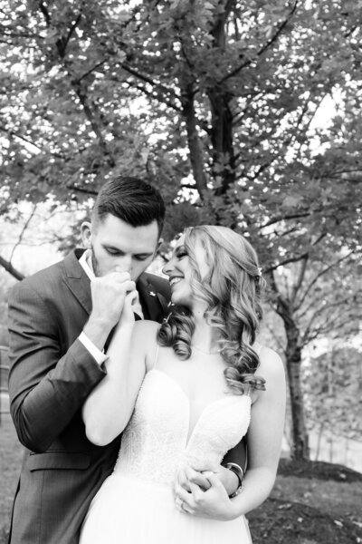 man kissing woman's hand on wedding day in black and white image