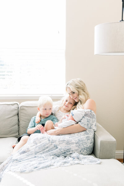 New mother and three children snuggling together on couch taken by Newborn Photographer Sacramento Kelsey Krall