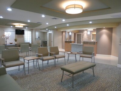 This modern urgent care center  features a waiting area, reception area, front desk, nurses station, and exam rooms.