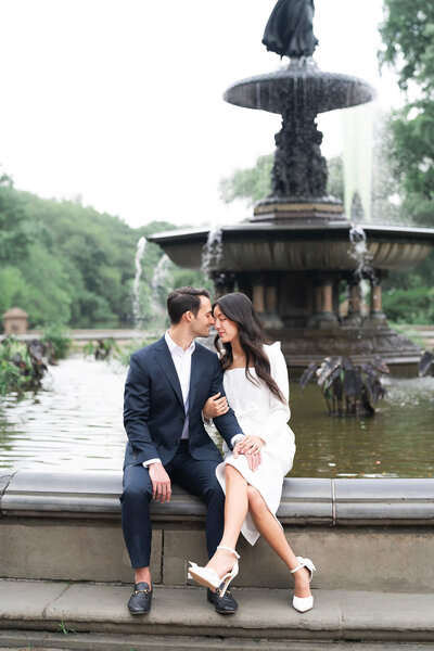 couple kisses in front of a fountain in Central Park on a cloudy day by Houston's best wedding photographers Swish and Click Photography