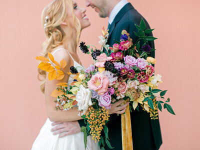 bride and groom smiling with colorful bouquet