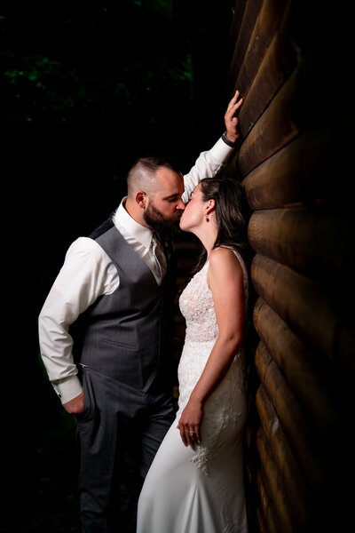 a groom leans in to kiss his bride with his hand on the wall above her head