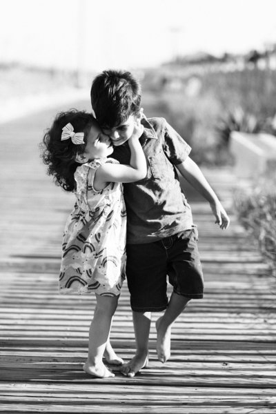 Young brother and sister hugging on the boardwalk