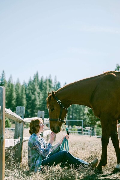 Senior girl session at Piping Rocks in Truckee. Girl sitting and horse wanting to get close
