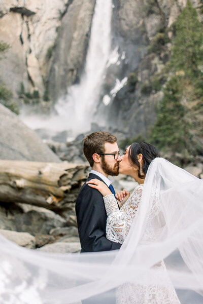Bride and groom pose against Yosemite Falls during their Yosemite National Parks elopement