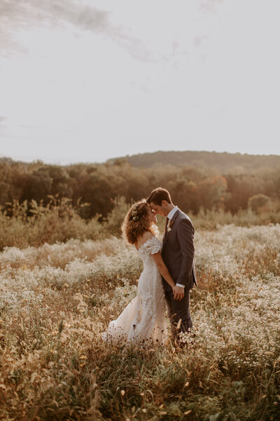 Wedding couple holding hands in flower field at sunset