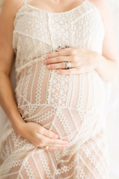 mom cradling belly in lace dress