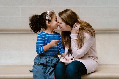 A parent and child sitting next to each other with their noses touching.