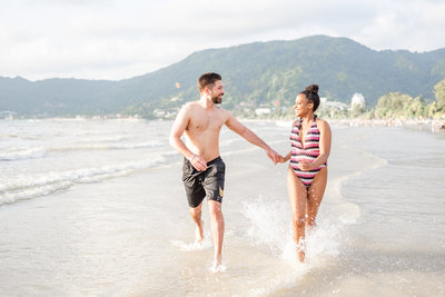 Couple engagement shoot on beach running through water