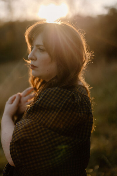 moody sunset golden hour outdoor brand headshot of Annie in natural light with rays of sunshine