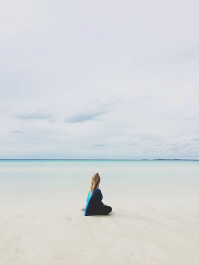 A Lone Blonde Woman Faces Away from the Camera on a Beach