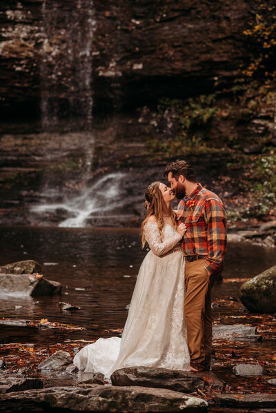 photo of newlyweds in front of a waterfall