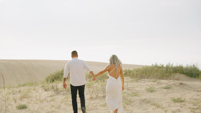 Couple walks on sand dune