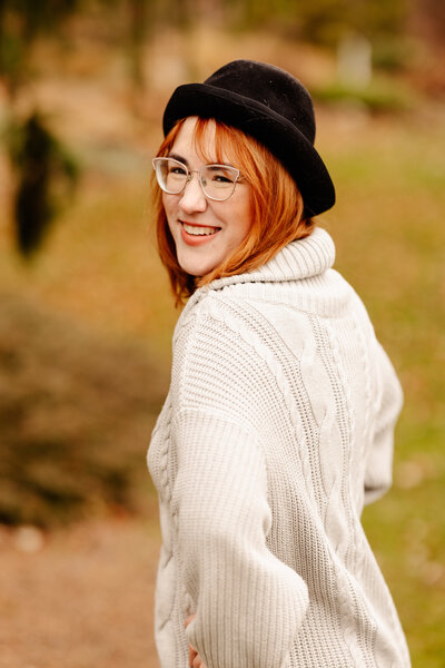 Woman in sweater and bowler hat smiles