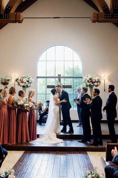 Bride and groom kissing in front of altar in Texas wedding