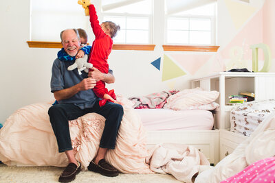grandpa playing with grandkids on bed in costumes during documentary family photography session in Denver, Colorado