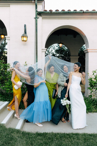 playful wedding photo of a bride and bridesmaids playing with her veil at Ebell of Los Angeles