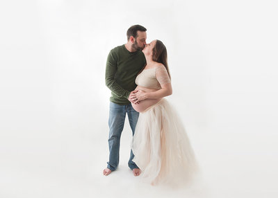 couple expecting baby sharing kiss during studio maternity session