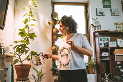 woman waters her plants in her apartment