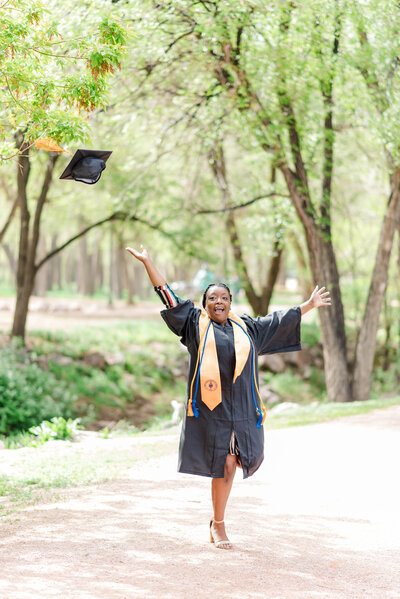 A new graduate tosses her graduation cap in the air celebrating her success at a Park in Colorado Springs by Laramee Love Photography