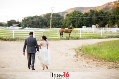 Bride and Groom go for a walk as the Groom holds her dress train off the ground at the Hold Out Ranch wedding venue in Castaic, CA