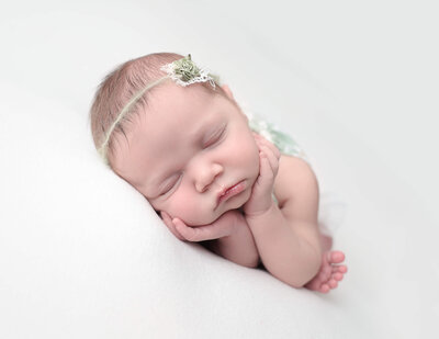 Sleeping newborn girl posed at our Rochester, NY studio.