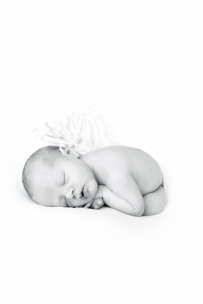 A B&W  newborn baby sleeping in froggy pose on a white bed