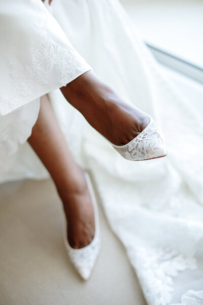A bride's feet elegantly adorned in wedding shoes, showcasing the beauty of a destination wedding setting.