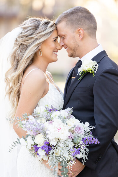 Bride and groom touching foreheads with bouquet at Treasury on the plaza