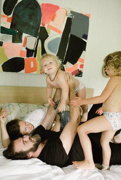Couple lying on bed with two toddlers in undies at family photoshoot in Austin