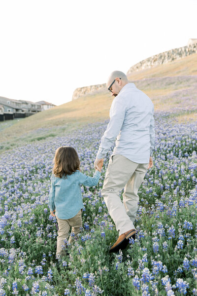 father and son walking in flowers together holding hands taken by Newborn Photographer Sacramento Kelsey Krall