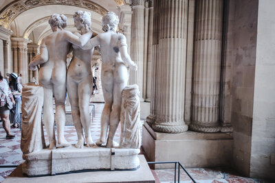The Three Graces, a marble statue of three women in a friendly embrace, inside the Louvre museum