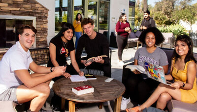 Smiling students sitting around an outdoor table on campus