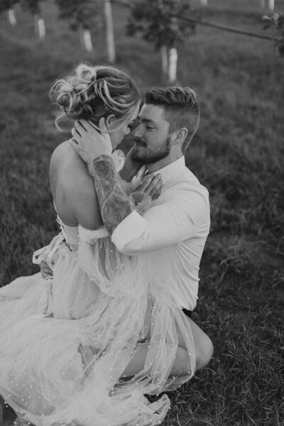 groom kissing bride in a grass field