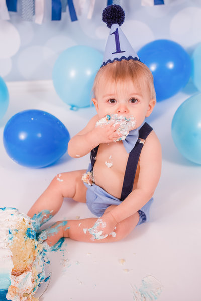 Little boy smashes cake into his mouth during cake smash photography session