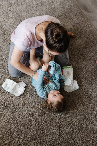 a mom changing her child's diaper on the carpet