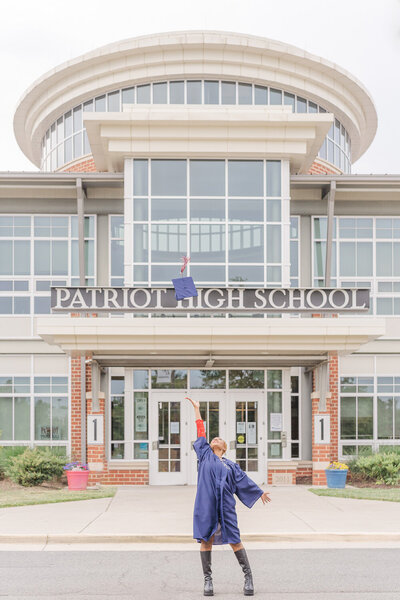 high school girl wearing graduation gown throwing cap outside her school for her Nokesville, VA senior photos