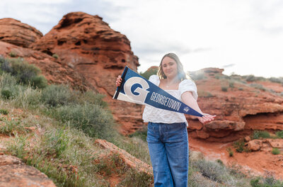 girl holding a college banner and posing for senior photos