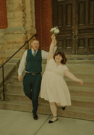 a bridal party look around at eachother and laugh while walking away from a rustic barn