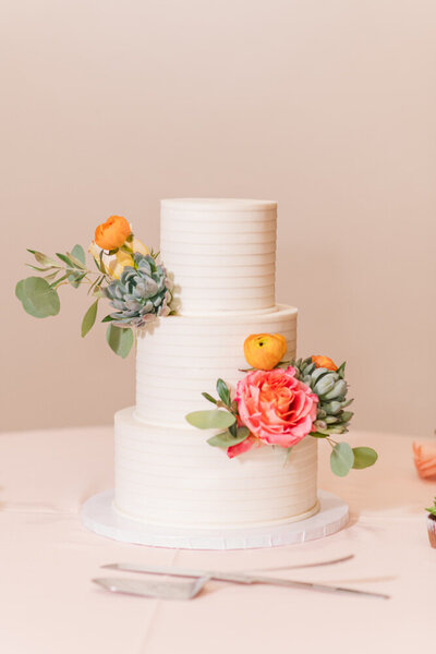 simple white wedding cake with colorful spring flowers