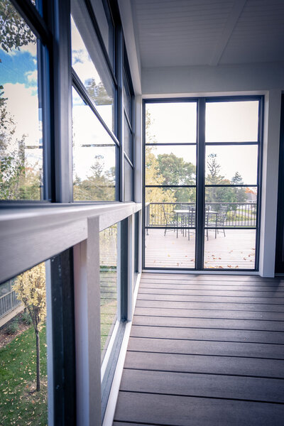 Inside an empty 3-season porch with floor-to-ceiling 4-track vinyl windows. 