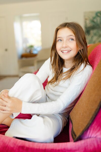 Girl smiling big in vibrant couch at in-home family session in Lexington KY.